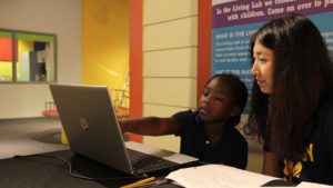 Children visiting the Ann Arbor Hands-On Museum, like 5-year-old Lindsay Bennett from Detroit, can participate in research through the U-M Living Lab. Psychology student Coral Lu is asking Lindsay questions about the cost of items to gauge her understanding of supply and demand. (Photo by Jacob Levi Stroud)