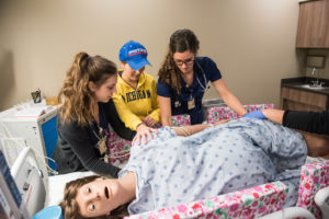 U-M Nursing students turn the Victoria mannequin on her side during a programmed seizure. Credit: Michigan Photography