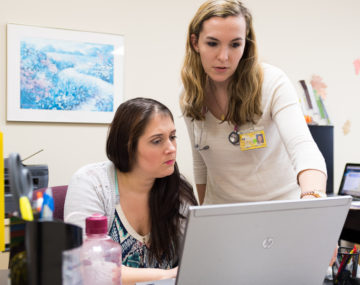 Two women examine a laptop screen at the U-M student-run clinic