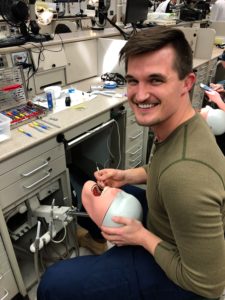 Dental Student posing with model of human head while performing dental procedure