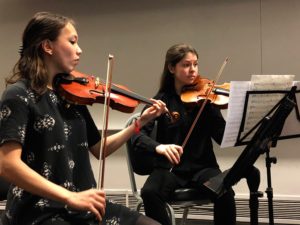 Two female students perform with their violins.