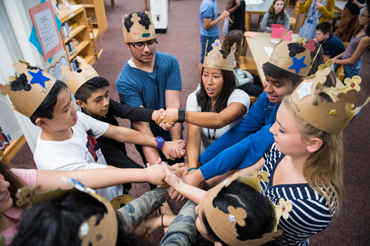 College students and middle school students participate in a team building exercise where they join hands with the person across from them and then untangle into a perfect circle without letting go of anyone's hand