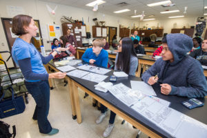 LSA Outreach Coordinator Jenna Munson guides students through an interactive science activity. From left are Keegan Beznoska, Jeiny Tavarez and Cung Bawi. (Photo by Peter Matthews, Michigan Photography)