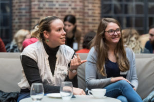 Two women sit, chatting and smiling in the Kresge Court