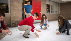 A few students squat in the snow, collecting enough to put in petri dishes.