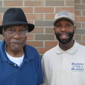 Buddy to Buddy employee stands next to WWII veteran, both smiling.