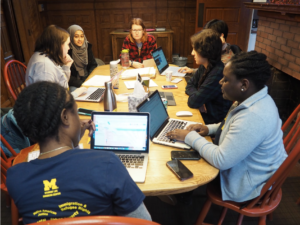 Students sit around a table looking at their computers.