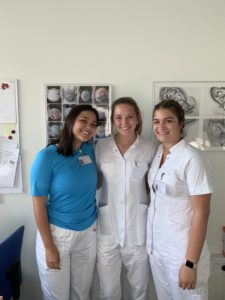 3 women pose in front of anatomy posters