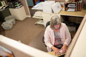 A person works in a cubical with a mask on. 