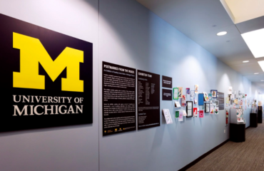 image shows a display of greeting cards along the wall as well as the UM logo