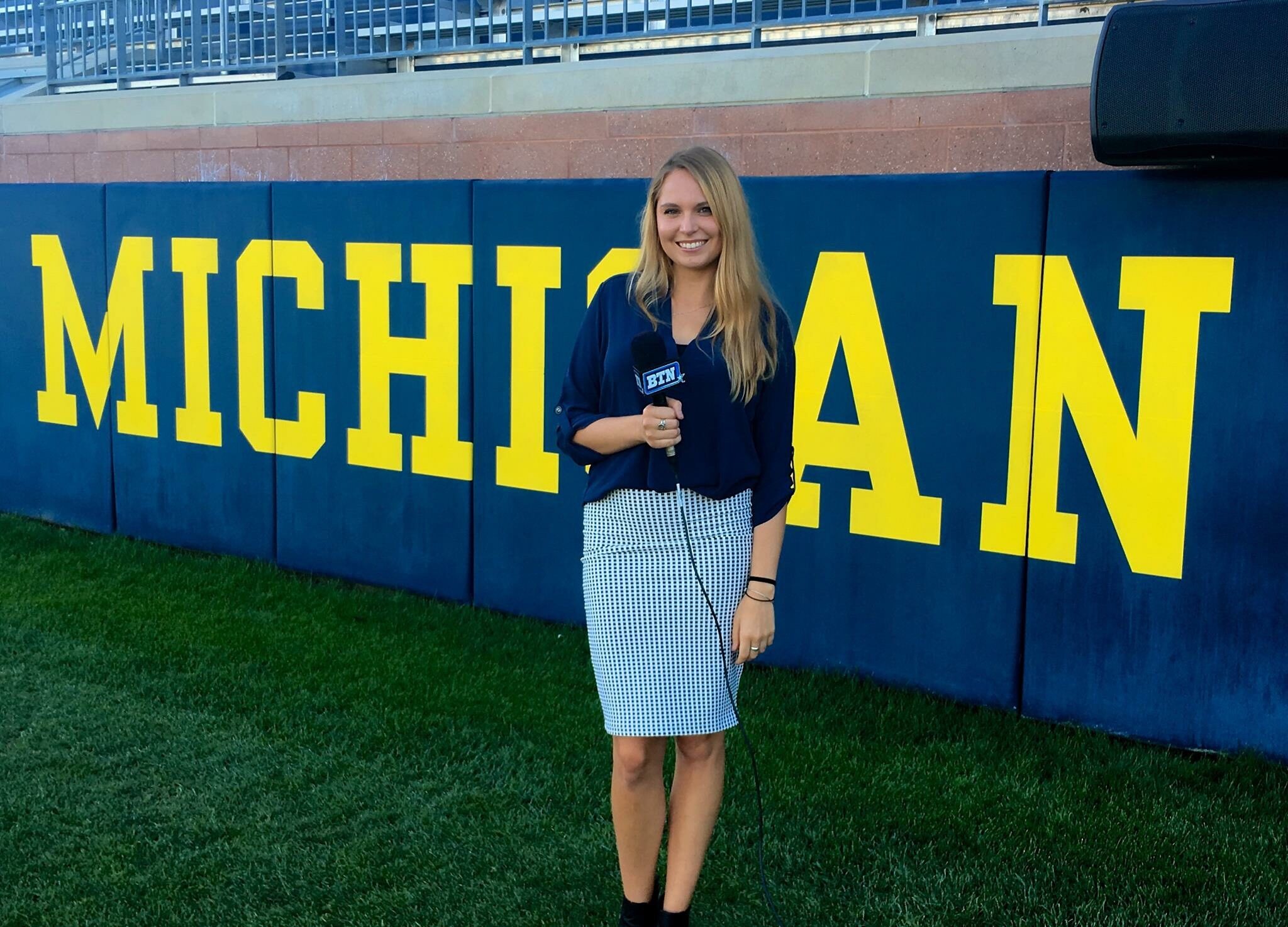 Riley Nelson stands in front of word "Michigan" in Michigan Football Stadium