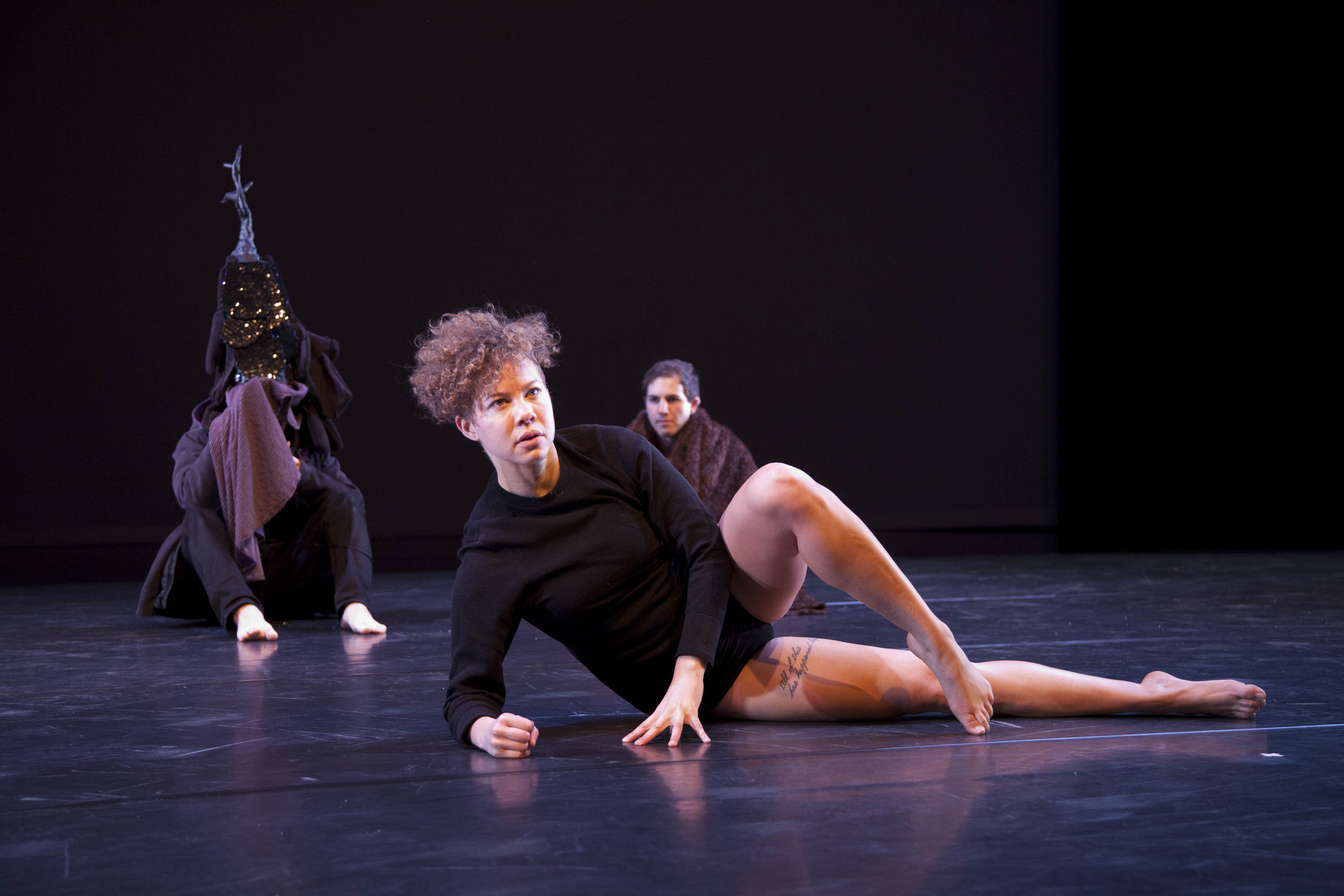 Anne Marie Whitehead poses in a black leotard, two other dancers in the background.